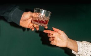 a mans handing a glass of whiskey to a woman