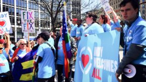 protesters wearing indy welcomes all shirts and carrying indy welcomes all banners