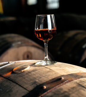 a glass of fortune's fool whiskey siting on a barrel