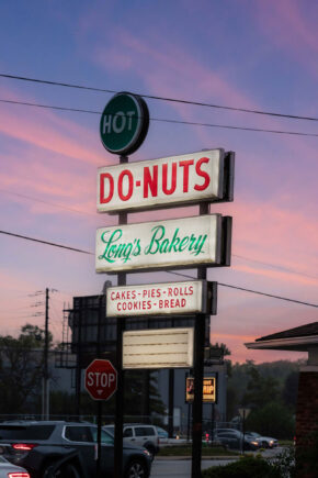 photograph of the monument sign in front of Long's Donuts with a vibrant sunrise in the background
