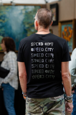 a man wearing a black tee shirt with a variety of speed city logos on it