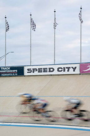 cyclists racing in the velodrome with a speed city banner in the background